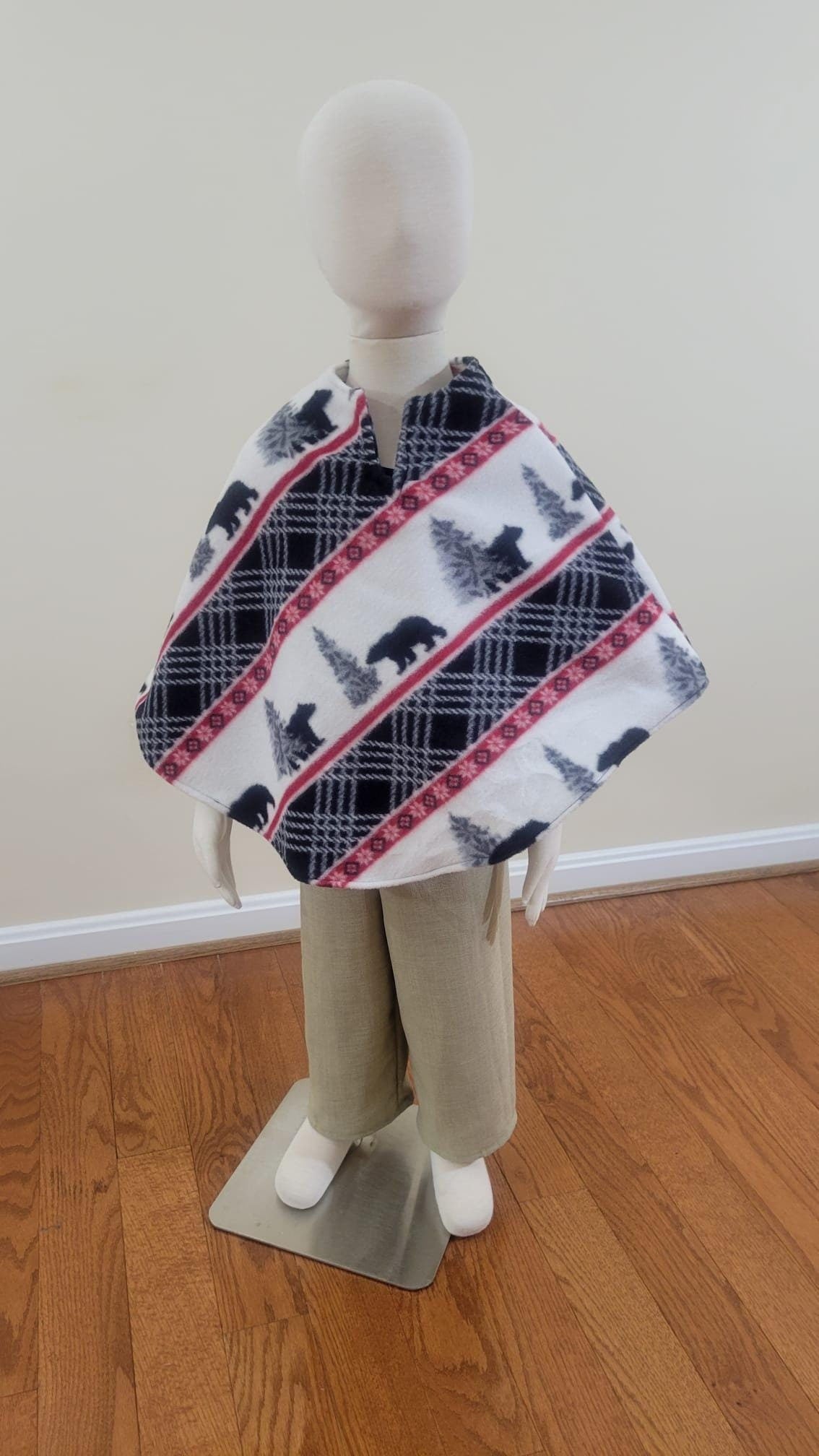 toddlermannequin wearing khaki pants and fleece circular poncho with bears and pine tree printed on it.